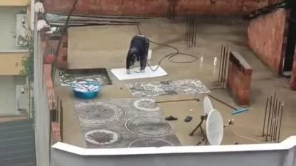 Yağmurlu havada çatıda halı yıkadı